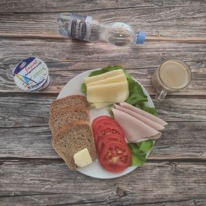 Zdjęcie przedstawia Dietę z ograniczeniem łatwoprzyswajalnych węglowodanów: Chleb Graham Masło extra Szynka tostowa Ser żółty Pomidor Kawa zbożowa z mlekiem Jogurt naturalny Woda źródlana Sałata zielona
